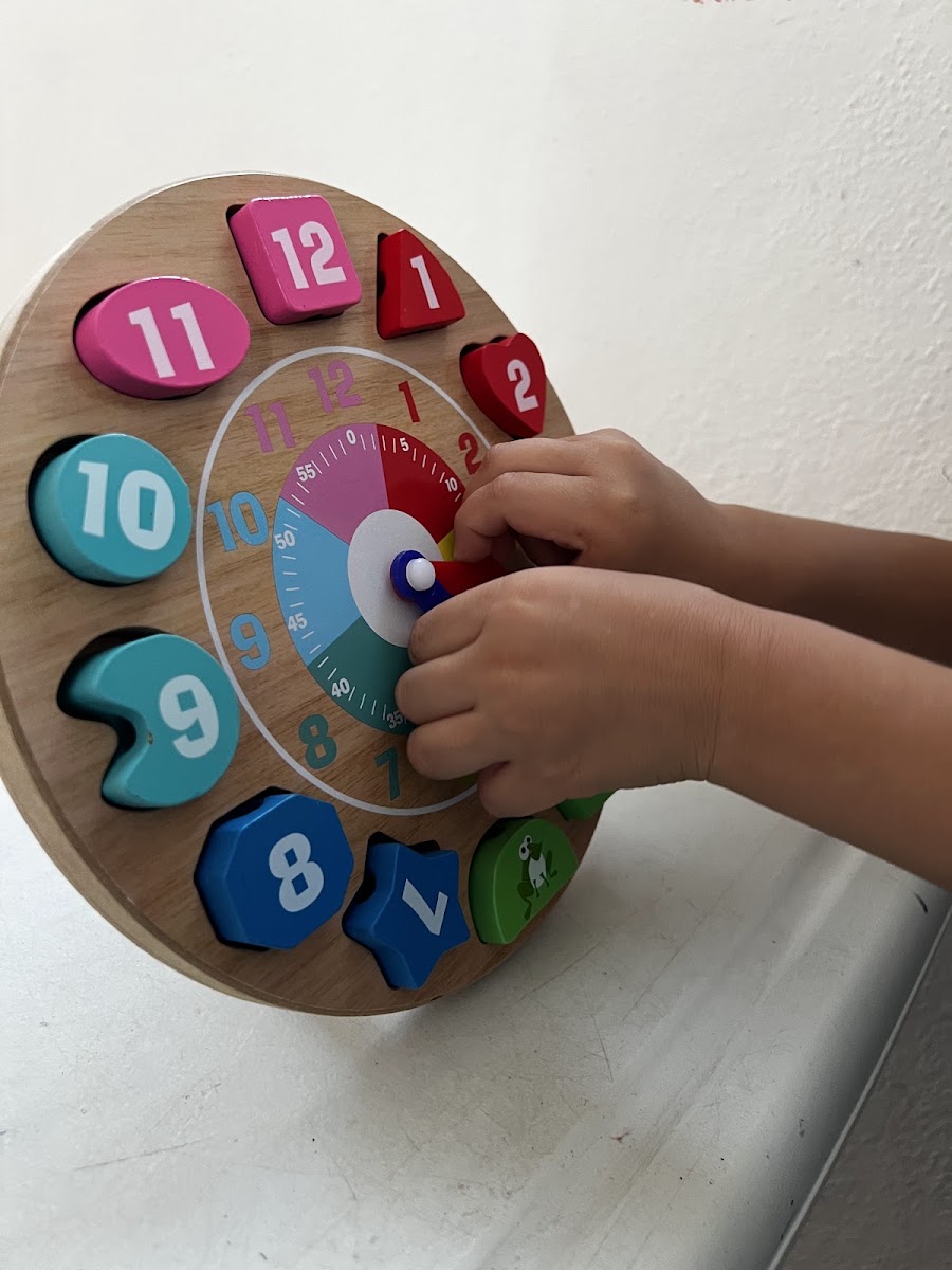 Niño aprendiendo con reloj didáctico
